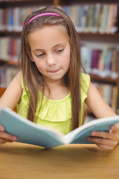 istock Pupil reading book at desk in library 486149100