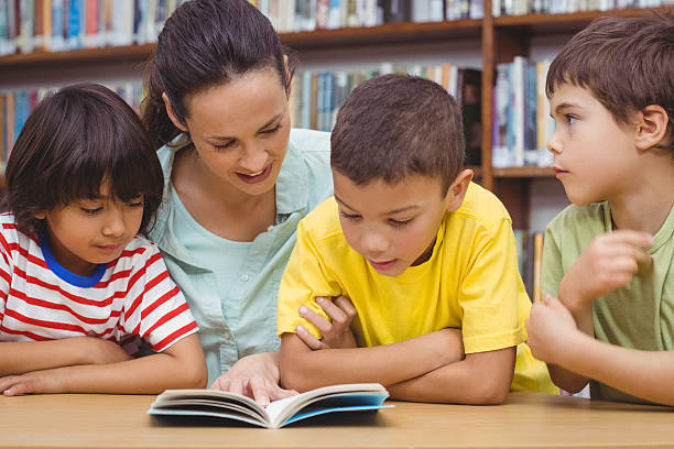 istock Pupils and teacher reading book in library 486149208