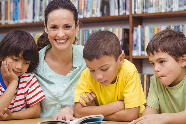 istock Pupils and teacher reading book in library 486149224