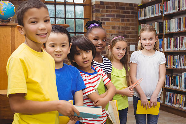 istock Pupils holding books from shelf in library 486149340