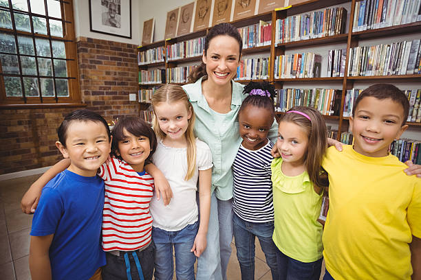 istock Pupils and teacher smiling at camera in library 486149668
