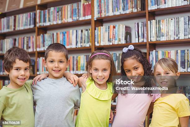 Pupils Smiling At Camera In Library Stock Photo - Download Image Now - 2015, 6-7 Years, 8-9 Years