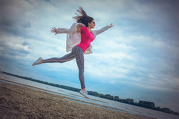 счастливый молодая женщина, бег и прыжки на пляже - arms outstretched teenage girls jumping flying стоковые фото и изображения