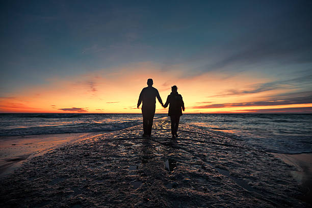 Senior couple walking from seashore at sunset