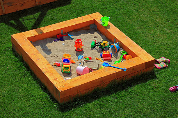 Sandbox playground with lots of toys A nice sandbox playground filled with lots of toys. Surrounded by green grass, seen from top. sandbox stock pictures, royalty-free photos & images