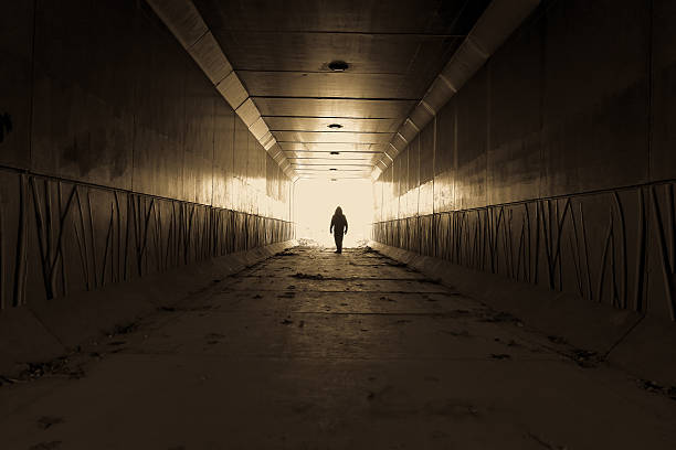 Stranger Danger Silhouette of a male waiting at the end of a dark alley. creepy stalker stock pictures, royalty-free photos & images
