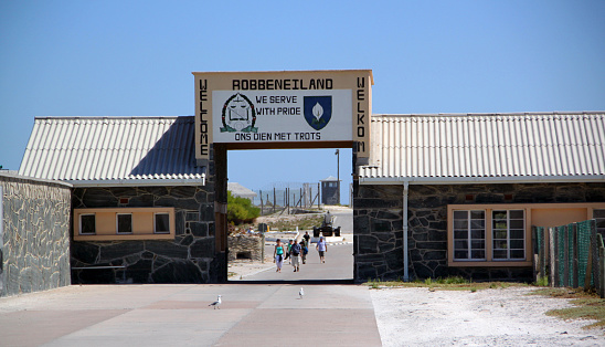 Cape Town, South Africa - March 12, 2012: Visitors pass through the entrance of Robben Island, the infamous island prison that held Nelson Mandela for 18 of his 27 years of his incarceration during the apartheid regime. The prison is now a museum.