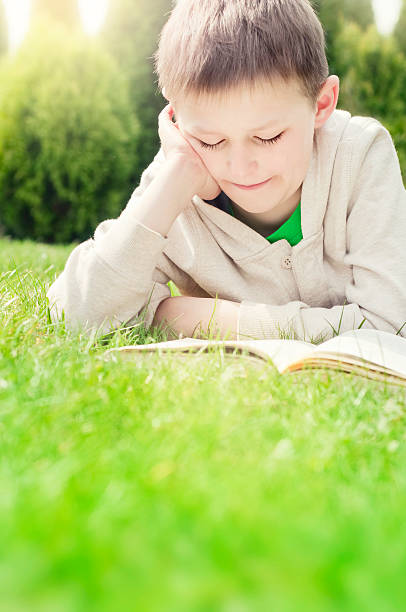 istock Boy reading book outdoors 486168115