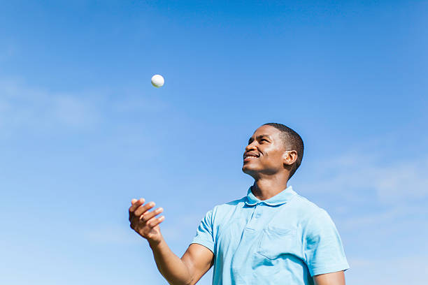 African golfer throwing his golf ball in the sky.