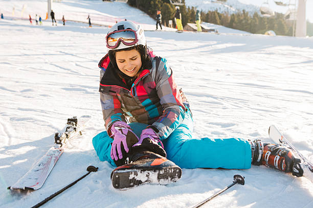 Teenage girl skiing in Italian Alps. Teenage girl skiing in Italian Alps, sitting on snow and holding her injured leg. Winter, daytime. Sunny weather. ski injury stock pictures, royalty-free photos & images