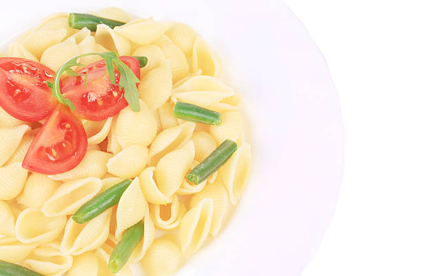 Pasta shells with vegetables on white plate.