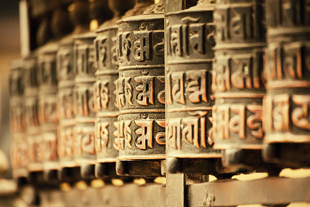 Prayer Wheels, Kathmandu, Nepal A prayer wheel is a cylindrical wheel on a spindle made from metal, wood, stone, leather or coarse cotton. Traditionally, the mantra Om Mani Padme Hum is written in Sanskrit on the outside of the wheel.  Image has been captured in Swayambhunath Stupa  (dates back to 16th century) which is one of the holiest Buddhist sites in Kathmandu, Nepal. prayer wheel nepal kathmandu buddhism stock pictures, royalty-free photos & images