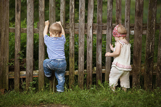 istock boy and girl climbs the fence 486170151