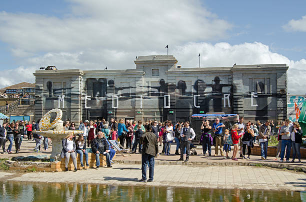 Mediocre Dismaland Weston-Super-Mare, UK - August 26, 2015:  Visitors crowding the proudly 'mediocre' Dismaland theme park inspired by Banksy and erected in a disused swimming pool in the Somerset resort of Weston-Super-Mare. banksy stock pictures, royalty-free photos & images