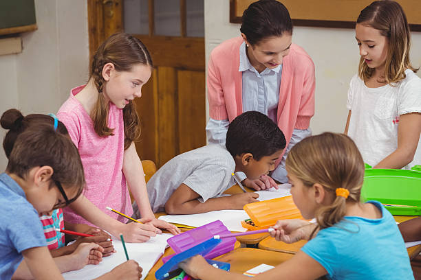 istock Teacher and pupils working at desk together 486172574