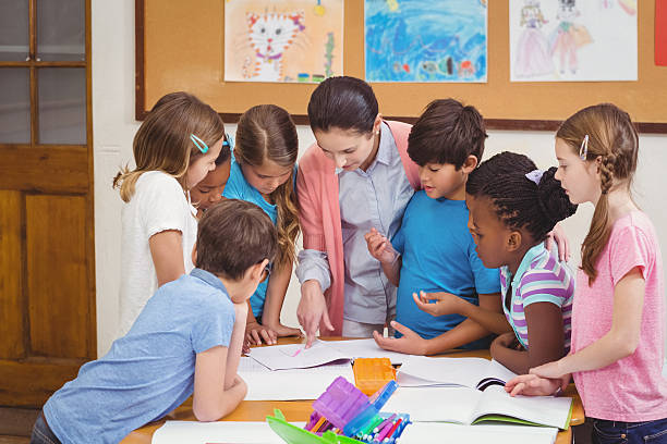 istock Teacher and pupils working at desk together 486172874