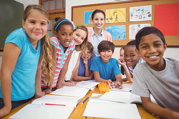 istock Teacher and pupils working at desk together 486172880