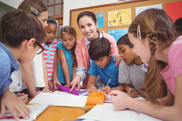 istock Teacher and pupils working at desk together 486178642