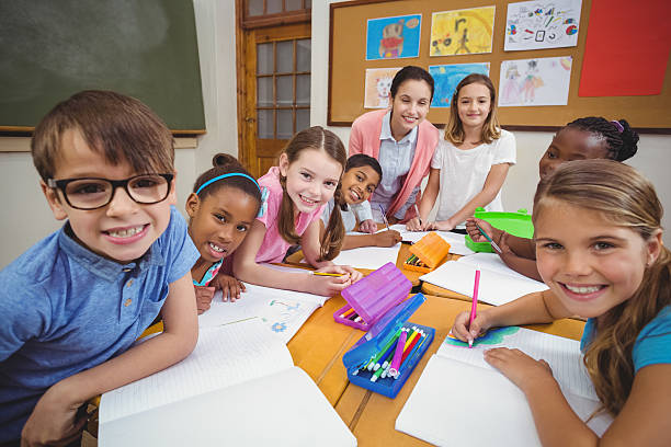 istock Teacher and pupils working at desk together 486183976