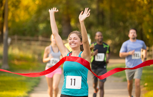 Young adult female crossing the finish line with ribbon