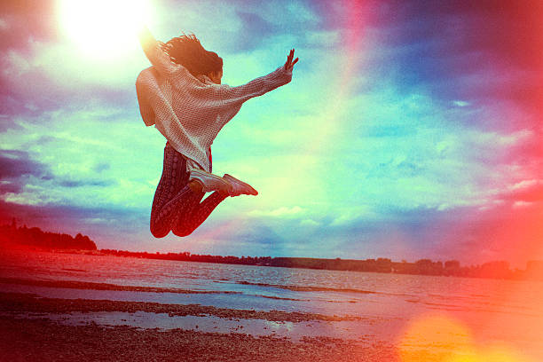 heureuse jeune femme courir et sauter sur la plage - beach nature outdoors overcast photos et images de collection