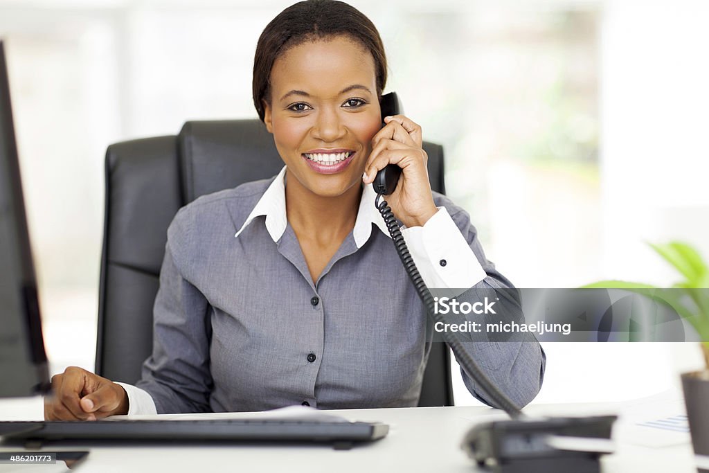 Afro-americana donna d'affari utilizzando il telefono fisso - Foto stock royalty-free di Usare il telefono