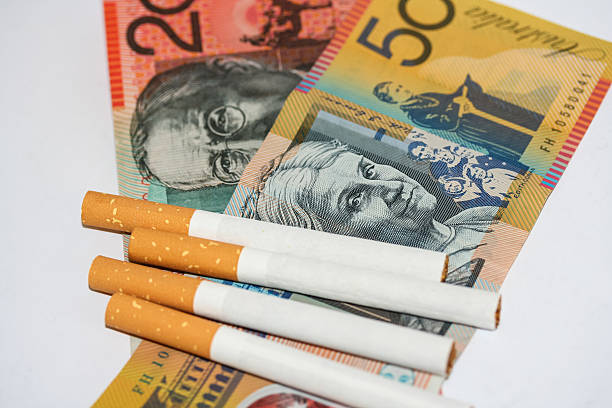 Tobacco cigarettes scattered on top of notes. stock photo