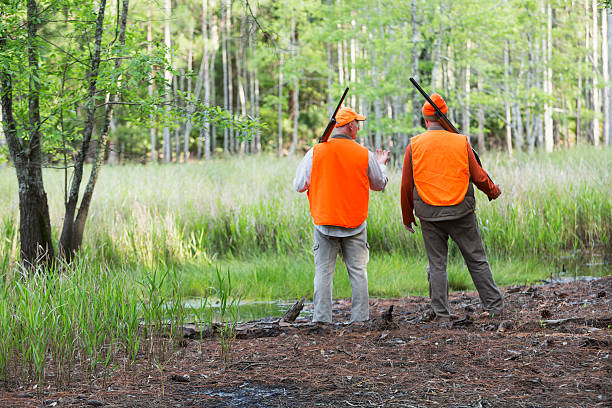 Backs of two hunters looking at woods