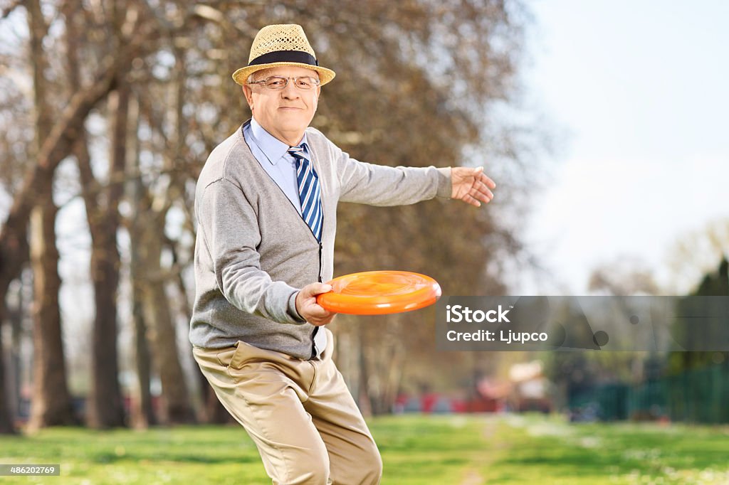 Senior man throwing a frisbee disk outdoors Senior man throwing a frisbee disk in a park 60-69 Years Stock Photo