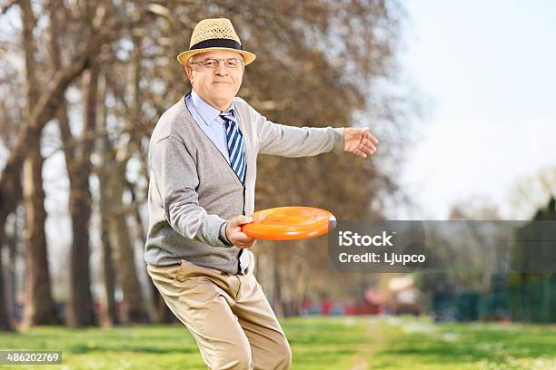 Senior Man Throwing A Frisbee Disk Outdoors Stock Photo - Download Image Now - 60-69 Years, Active Lifestyle, Active Seniors