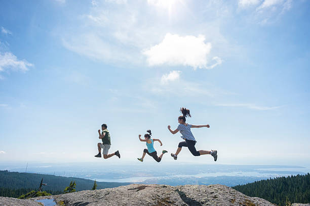 tres personas ejecutar y en la cima de la montaña, saltar del acantilado edge - family sport exercising jogging fotografías e imágenes de stock