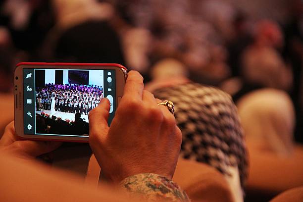 Abu Dhabi, UAE, June 13, 2015: An old lady using a Samsung mobile phone to snap a shot during a school graduation ceremony