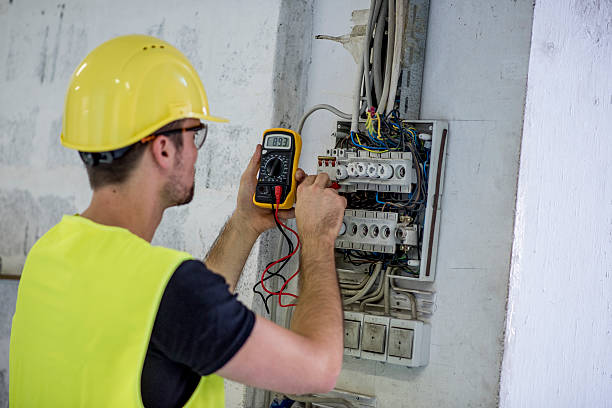 Electrician Testing Voltage Electrician, wearing protective helmet, glasses and reflective vest testing voltage  on construction site. multimeter stock pictures, royalty-free photos & images