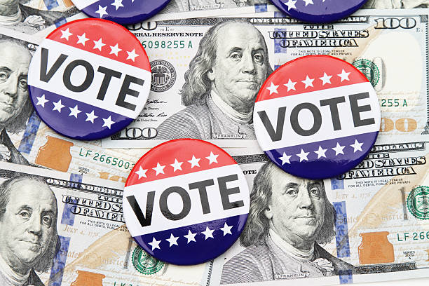 VOTE campaign buttons on top of hundred dollar bills stock photo