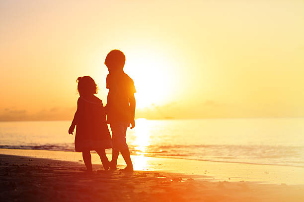 istock little boy and girl walking on sunset beach 486253068