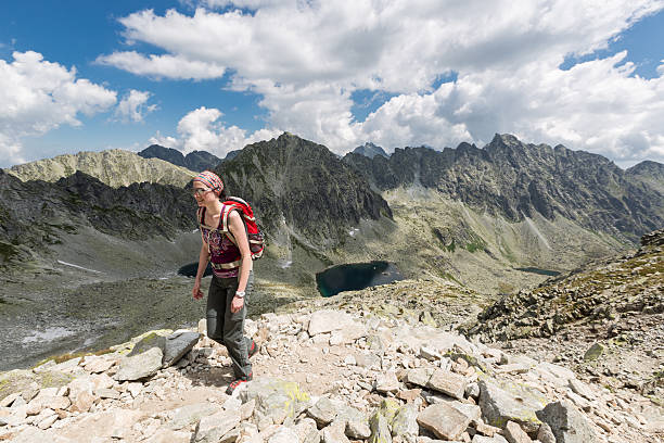 A female hiker is ascending on a rugged trail to the near summit in the High Tatra Mountains, Slovakia.  The High Tatras - having 17 peaks over 2,500 metres (8,200 ft)- are a mountain range along the border of northern Slovakia and southern Poland. The Region is very famous for hiking and skiing during winter time.