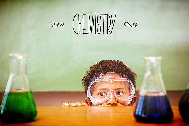 istock Chemistry against boy looking at conical flasks in classroom 486254614