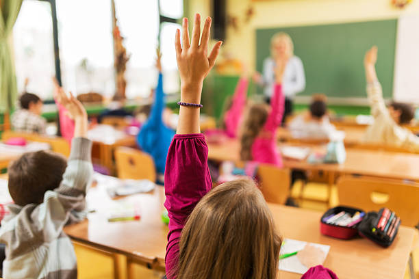 istock Rear view of elementary school children with raised arms. 486254954