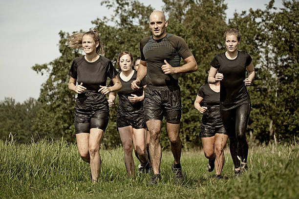 group of friends jogging outdoors during mud run group of friends jogging outdoors during mud run military camp stock pictures, royalty-free photos & images