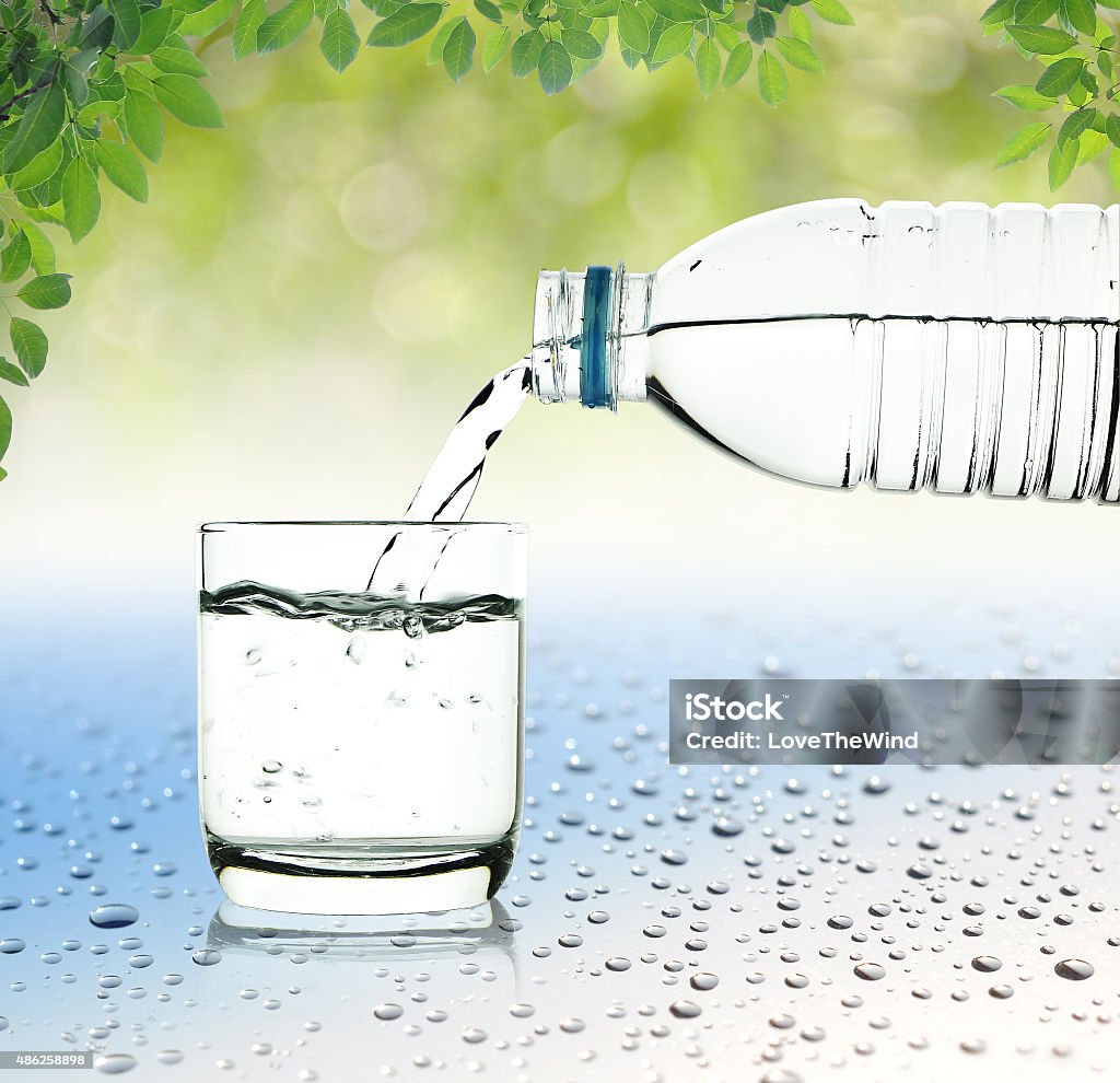 Drinking water is poured from a bottle into a glass 2015 Stock Photo