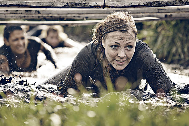 groupe de femmes de ramper dans la boue - mud run photos et images de collection