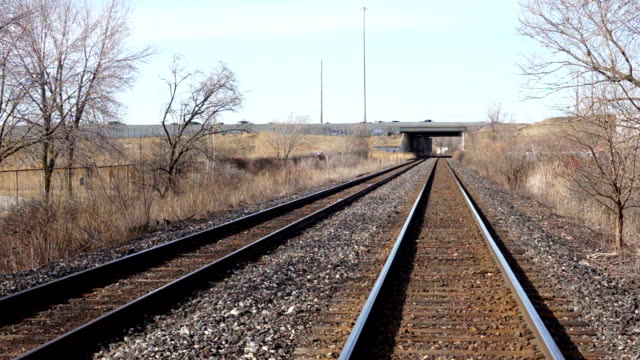 Railroad tracks through tunnel under highway with graffiti