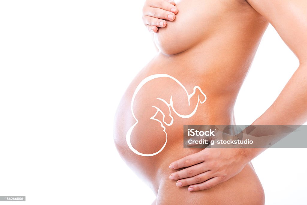 New life inside her. Close-up of pregnant woman holding hands on her abdomen while standing against white background 2015 Stock Photo