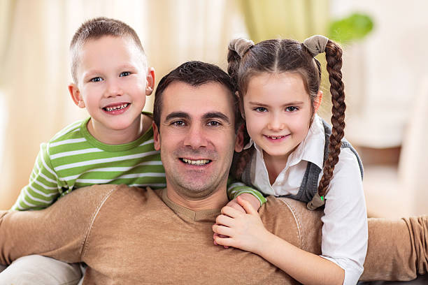istock Smiling children embracing their father and looking at camera. 486267596