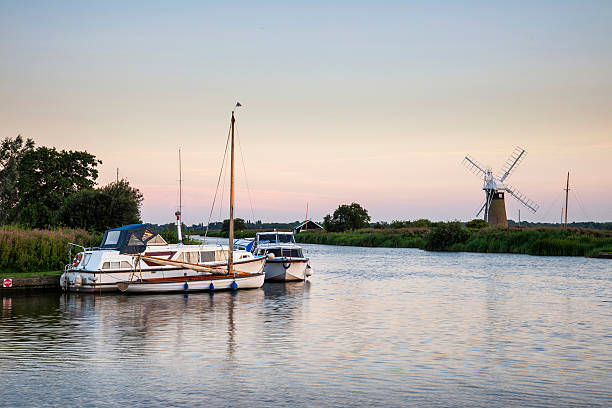 Stunning landscape of windmill and river at sunrise on Summer morning