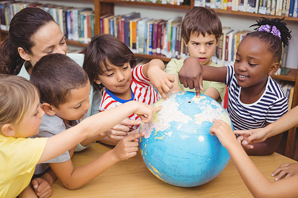 istock Pupils and teacher looking at globe in library 486271188