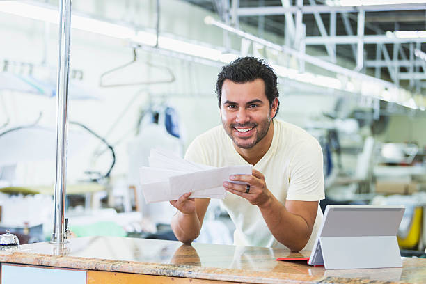 istock Hispanic small business owner, dry cleaner paying bills 486280060