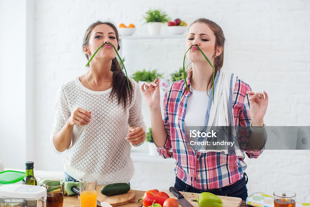 Women preparing healthy food playing with vegetables in kitchen having Women preparing healthy food playing with vegetables in kitchen having fun concept dieting nutrition. Cooking Stock Photo