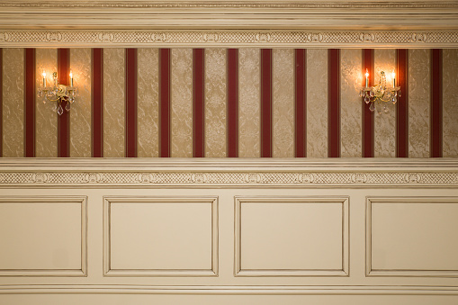 Formal interior wall with wallpaper, sconces and paneling