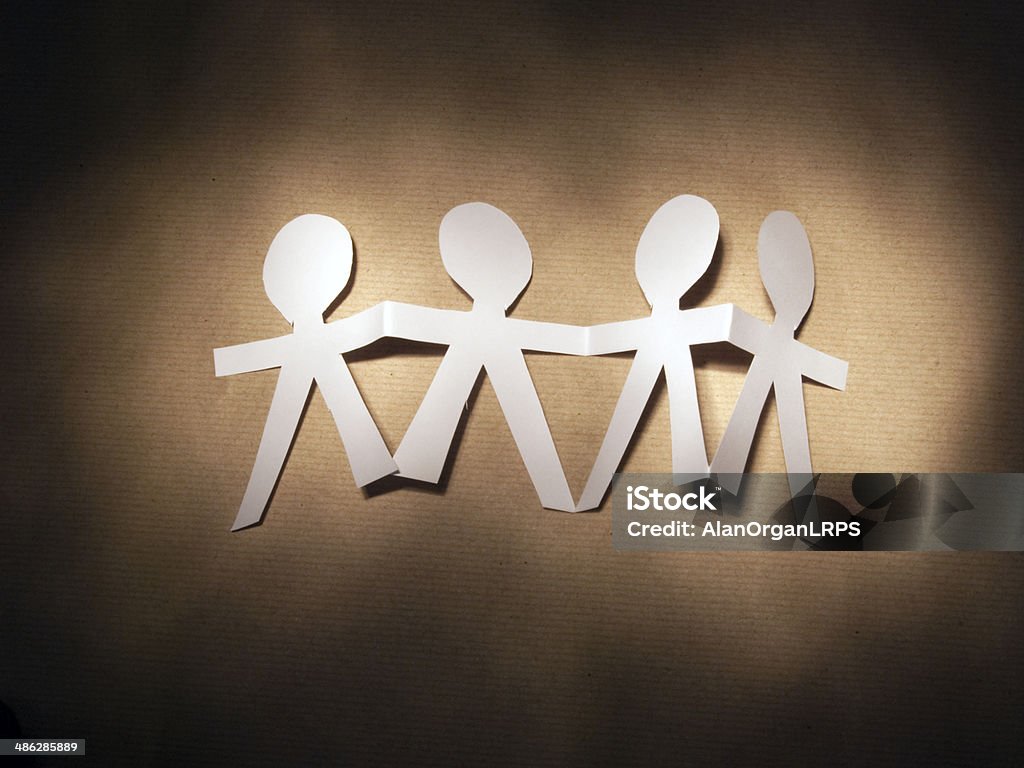 Paper Dolls Paper chain of four dolls on brown paper backing sheet. Quadruplet Stock Photo